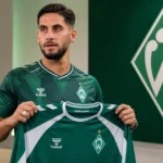 Ludovit Reis poseert met een Werder Bremen-shirt tijdens een officiële clubpresentatie.
