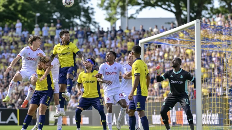 Spelers van Union en Zulte Waregem verdedigen samen een hoekschop voor doel.