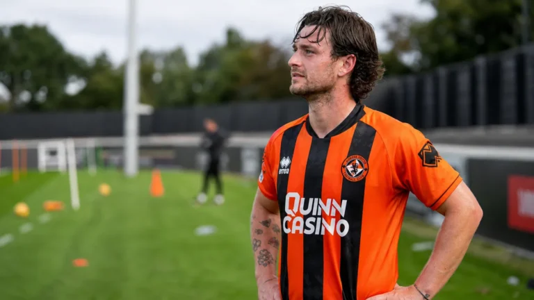 Will Ferry van Dundee United staat in zijn oranje-zwarte wedstrijdshirt naast het trainingsveld.