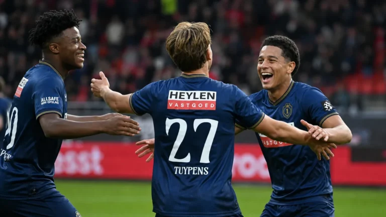 Drie spelers van Royal Antwerp FC vieren samen een doelpunt op het veld.