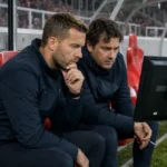 Technische staf bekijkt beelden op de bank in een Antwerpse stadionomgeving.