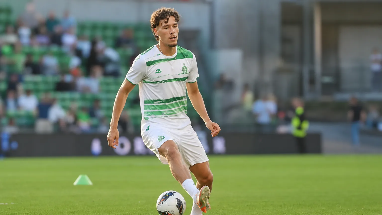 Lucas Stassin warmt op in een groen-wit voetbaltenue op het veld.