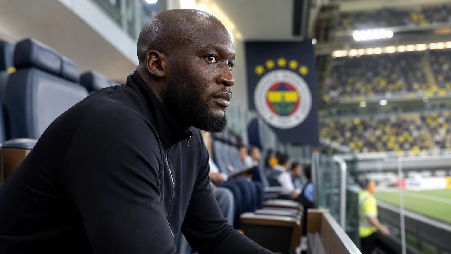 Romelu Lukaku kijkt geconcentreerd naar het veld vanuit de tribune van het stadion.