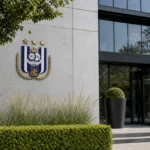 Ingang van een clubgebouw van RSC Anderlecht met een discreet clubembleem aan de gevel.