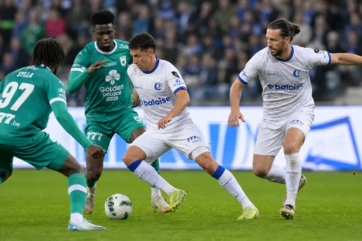 Spelers in witte en groene tenues in duel tijdens een voetbalwedstrijd.