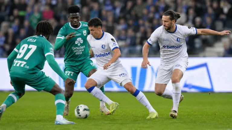 Spelers in witte en groene tenues in duel tijdens een voetbalwedstrijd.
