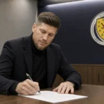 Sebastian Pocognoli ondertekent als nieuwe bondscoach een document in een ruimte van de Schotse voetbalbond.
