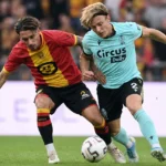 Twee voetballers van KV Mechelen en Standard in een luchtduel om de bal.