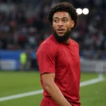 Arnaut Danjuma in een rood voetbalshirt aan de rand van het veld.