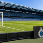Een leeg grasveld in het stadion van Club Brugge met een discreet clubbord langs de rand.