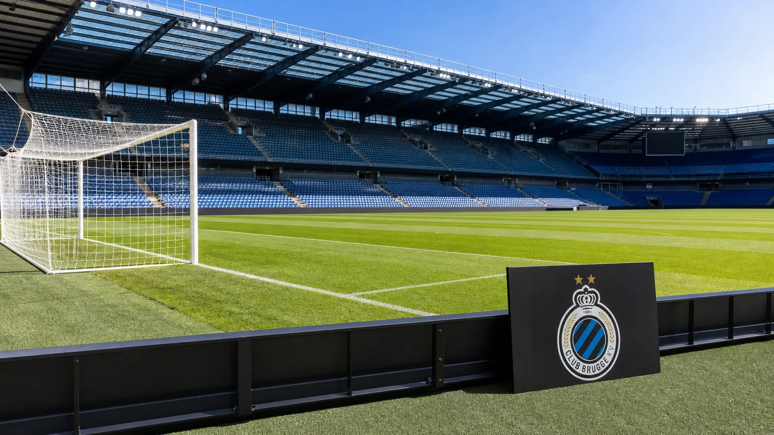 Een leeg grasveld in het stadion van Club Brugge met een discreet clubbord langs de rand.