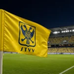 Een STVV-vlag naast het veld van een leeg stadion.