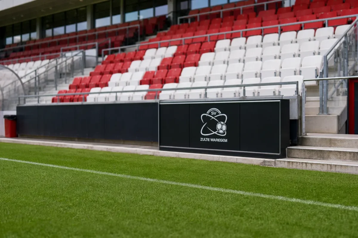 Zicht op de pitchside-zone van de Elindus Arena met een discreet logo van Zulte Waregem.