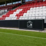 Zicht op de pitchside-zone van de Elindus Arena met een discreet logo van Zulte Waregem.