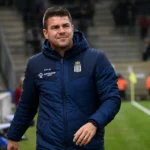 Mario Kohnen in een donkerblauwe coachjas langs de zijlijn na afloop van een wedstrijd.