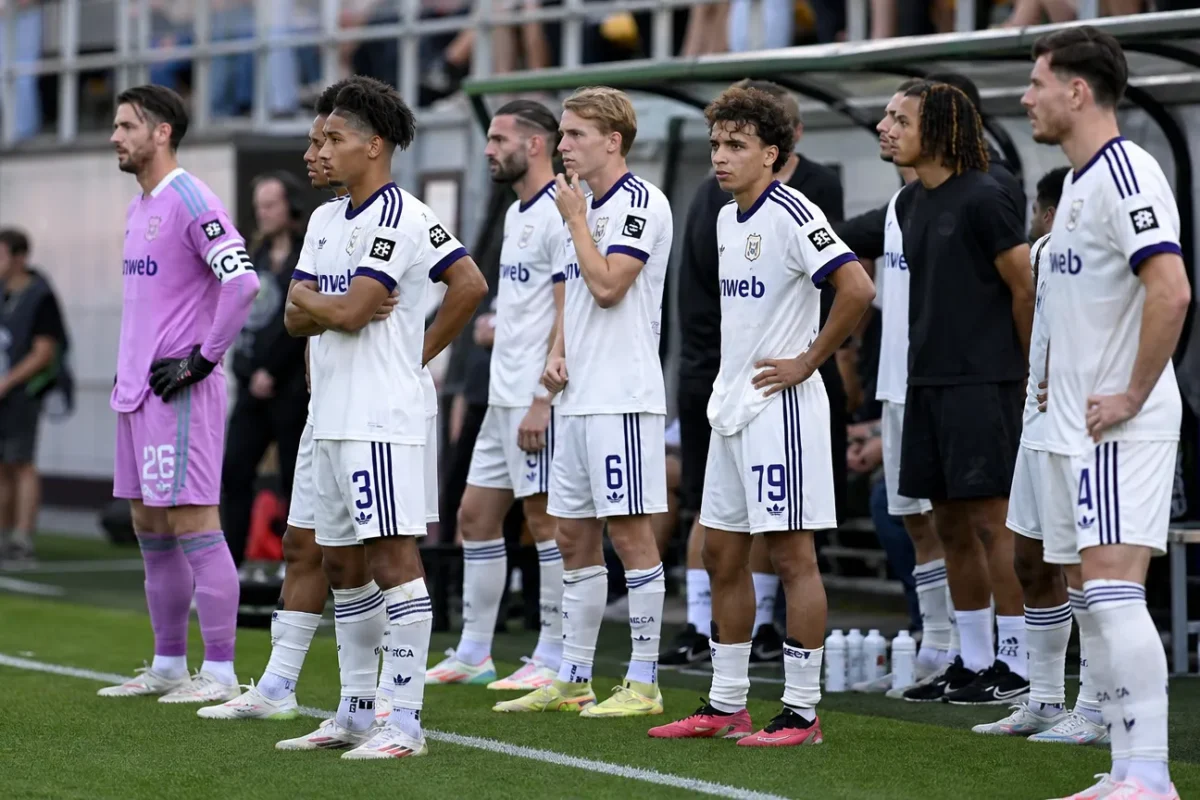 Een groep spelers van RSC Anderlecht wacht langs de zijlijn van het veld.