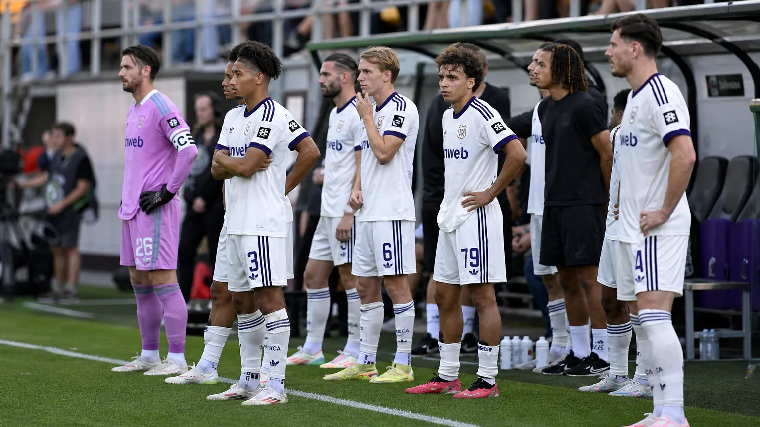 Een groep spelers van RSC Anderlecht wacht langs de zijlijn van het veld.