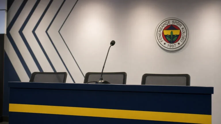 Een lege persruimte van Fenerbahçe met een microfoon en een discreet clubembleem op de achterwand.