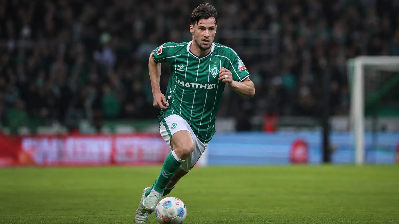 Olivier Deman in een groen gestreept voetbalshirt tijdens een actie op het veld.