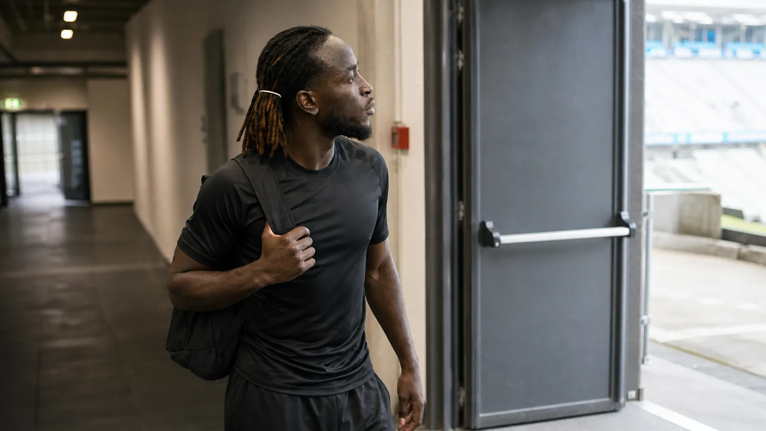 Parfait Guiagon in neutrale sportkleding bij een uitgang van een voetbalstadion.