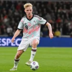 Joaquin Seys in een licht patroonshirt tijdens een actie op een verlicht voetbalveld.