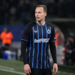 Gustaf Nilsson in het shirt van Club Brugge langs een voetbalveld.