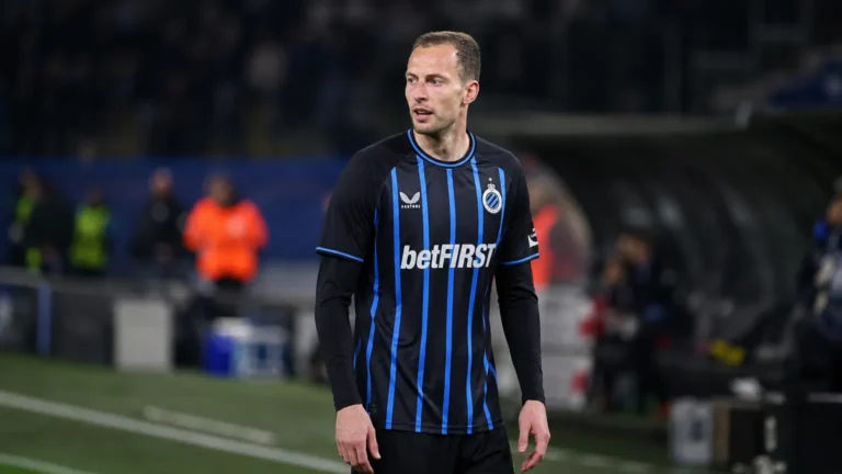 Gustaf Nilsson in het shirt van Club Brugge langs een voetbalveld.