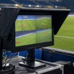 Een VAR-monitor naast het veld in een voetbalstadion.