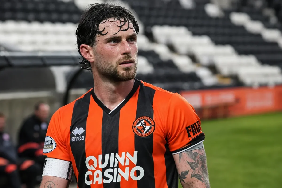 Will Ferry in het tenue van Dundee United langs de zijlijn van een voetbalveld.