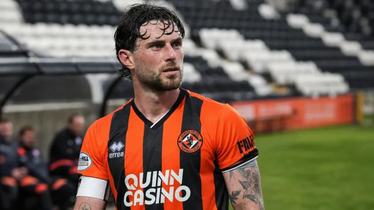Will Ferry in het tenue van Dundee United langs de zijlijn van een voetbalveld.