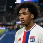 Malick Fofana in een witte spelersshirt in een stadionomgeving.