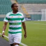 Michel-Ange Balikwisha wandelt in Celtic-tenue langs de zijlijn van een voetbalveld.