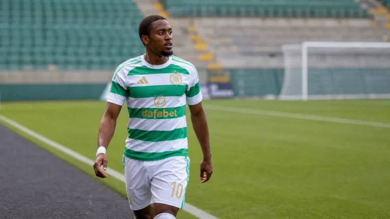 Michel-Ange Balikwisha wandelt in Celtic-tenue langs de zijlijn van een voetbalveld.