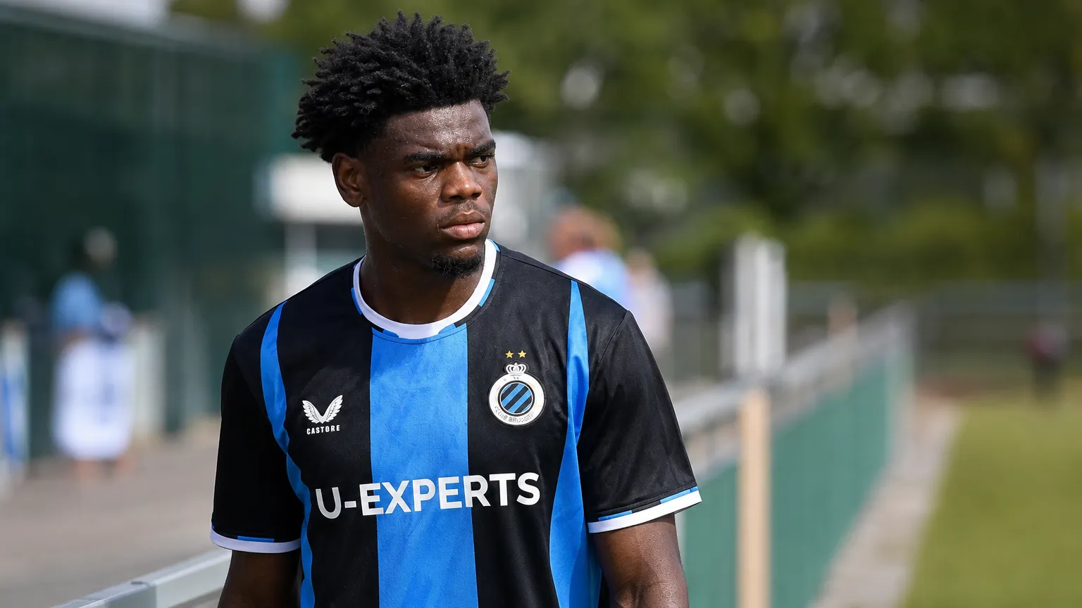 Vince Osuji in het blauw-zwarte shirt van Club Brugge langs de zijlijn.