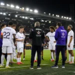 Een groep Anderlecht-spelers en stafleden op het veld in een verlicht stadion.