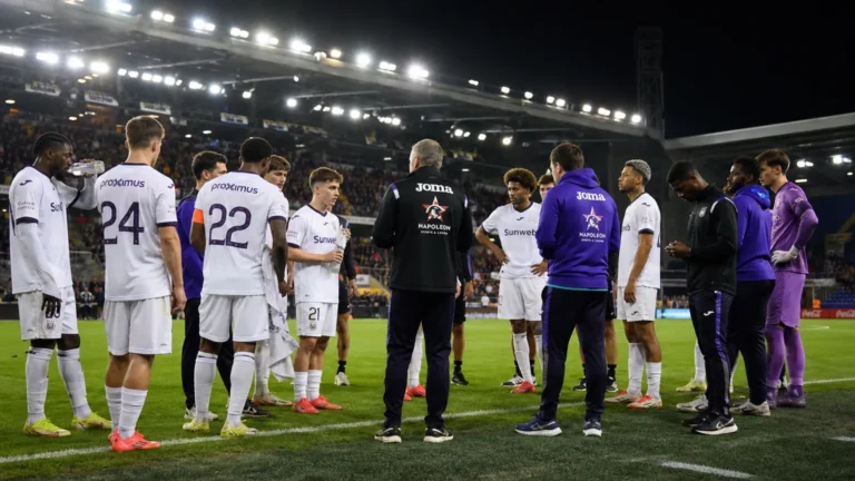 Een groep Anderlecht-spelers en stafleden op het veld in een verlicht stadion.