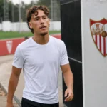 Lucas Stassin in neutrale trainingskleding naast een vast Sevilla-clubbord aan het oefenterrein.