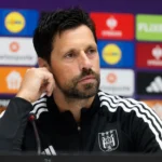 Een niet-spelende medewerker van RSC Anderlecht tijdens een persmoment voor een sponsorwand.