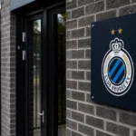 Lege ingang van een Club Brugge-clubgebouw met het clubembleem aan de gevel.