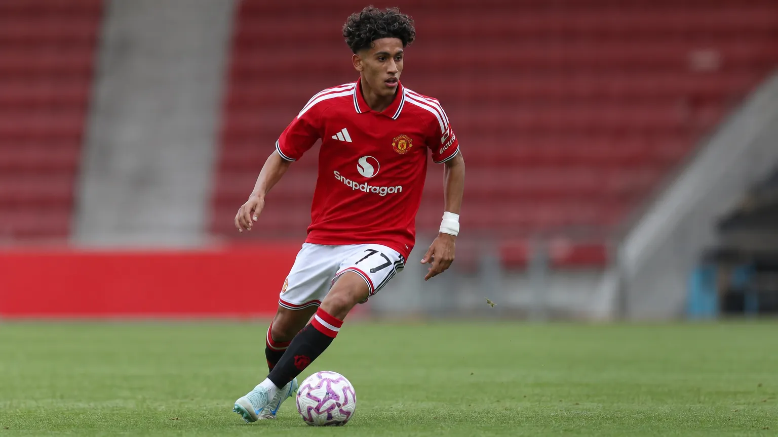 JJ Gabriel in het rode shirt van Manchester United op een voetbalveld tijdens een jeugdwedstrijd.