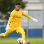 Lucca Brughmans in geel doelmanstenue tijdens een oefening met de bal op het trainingsveld.