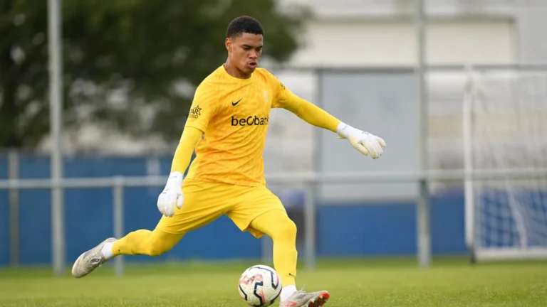 Lucca Brughmans in geel doelmanstenue tijdens een oefening met de bal op het trainingsveld.
