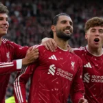 Drie Liverpool-spelers vieren op het veld na een wedstrijd.