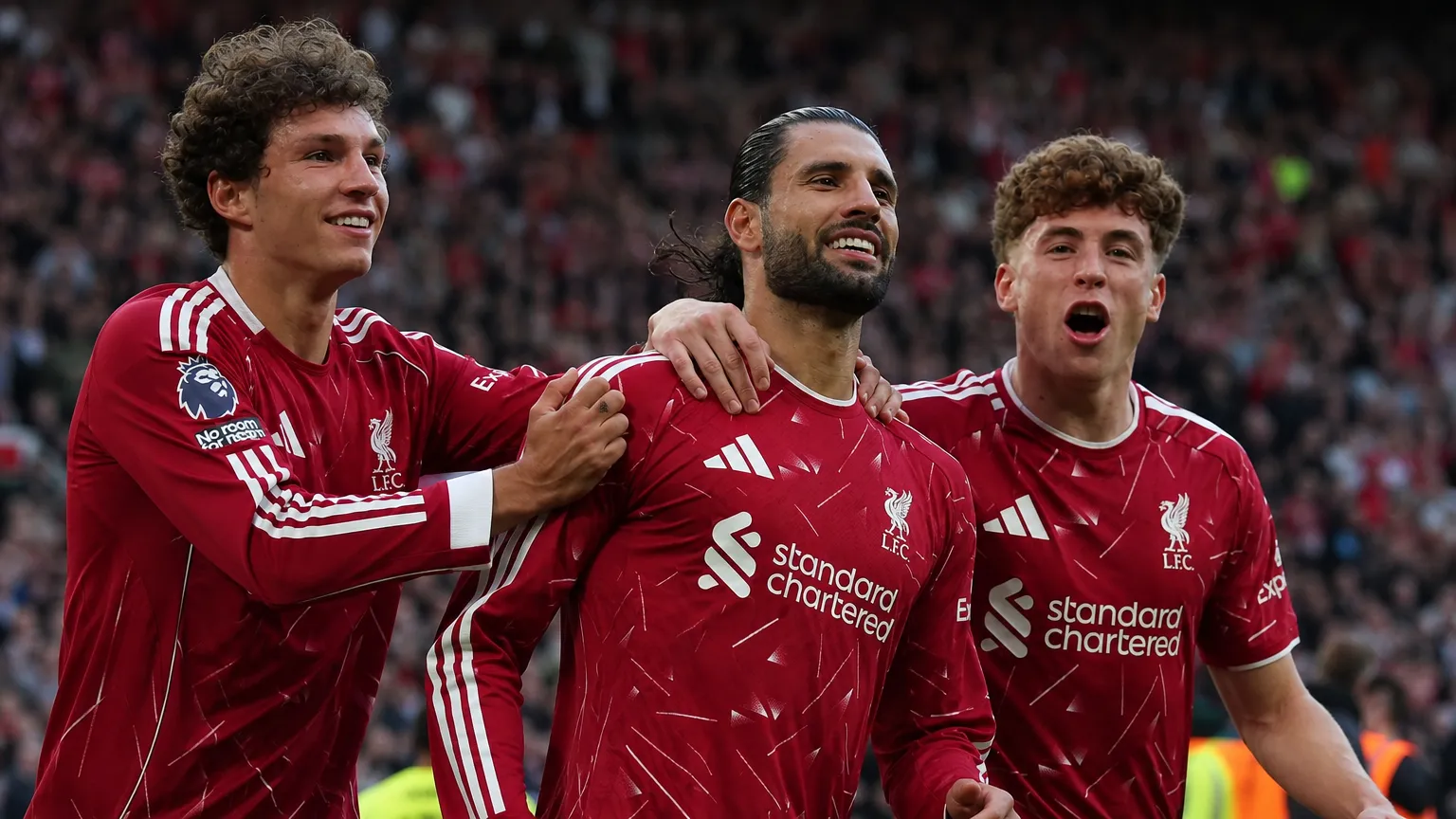 Drie Liverpool-spelers vieren op het veld na een wedstrijd.