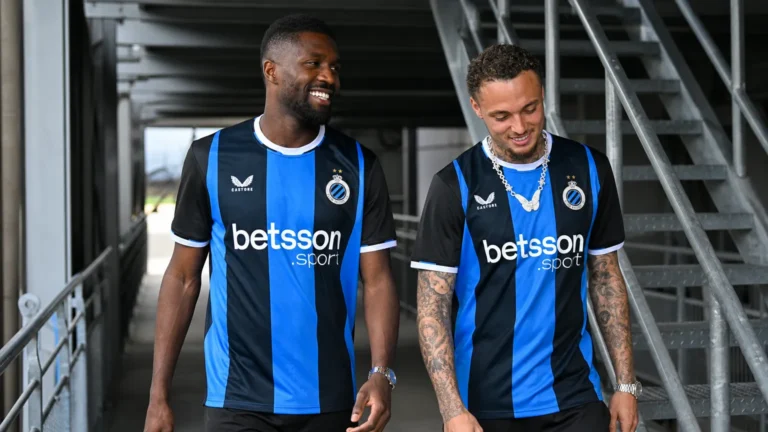 Twee voetballers in blauw-zwarte Club Brugge-tenues in een overdekte stadiongang.