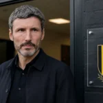 Mark van Bommel bij de ingang van het perslokaal in Tubeke, naast een wandplaat van de Rode Duivels.
