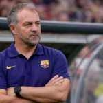 Een trainer in een donkerblauwe FC Barcelona-polo langs de zijlijn.