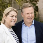 Een vrouw en man in nette kleding poseren samen op een rustige buitenlocatie.
