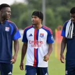 Drie voetballers in behouden trainingskleding tijdens een opwarming op het oefenveld.