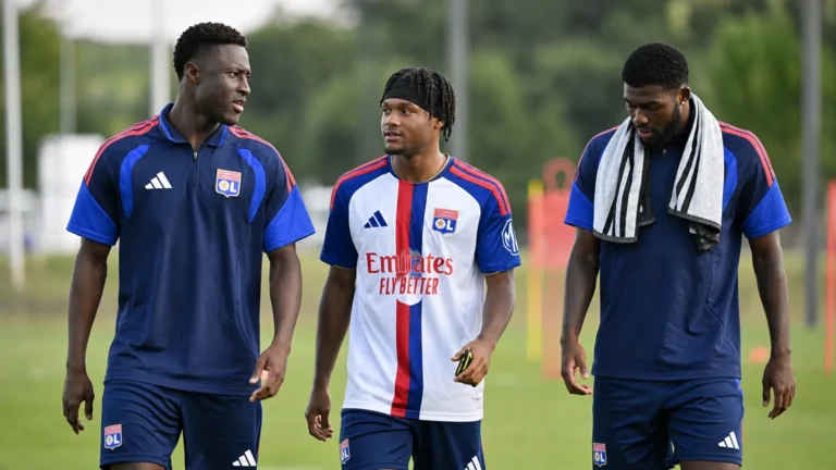 Drie voetballers in behouden trainingskleding tijdens een opwarming op het oefenveld.